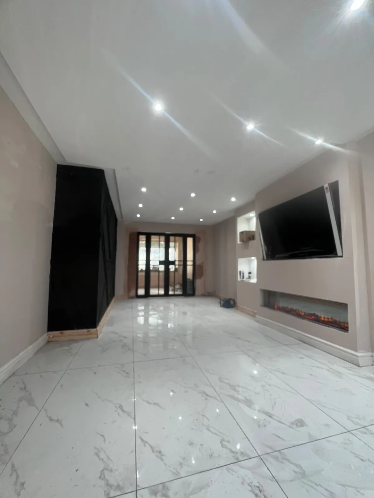 Open-plan lounge with fitted black storage and French doors, Upminster